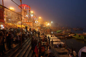 Nightime crowd people the steps leading down to the river Ganges in Varanasi, decorative lighting creates festival atmosphere, Varanasi, India.